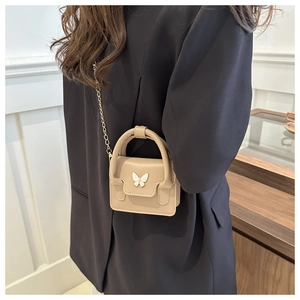 Detail of khaki mini square bag with golden chain and pearl butterfly buckle on model