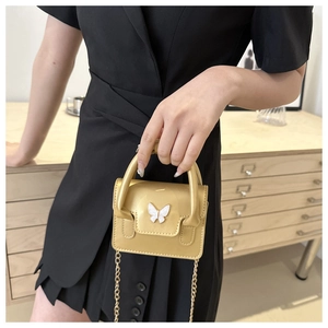 Detail of metallic yellow mini bag with pearl butterfly buckle and gold chain strap