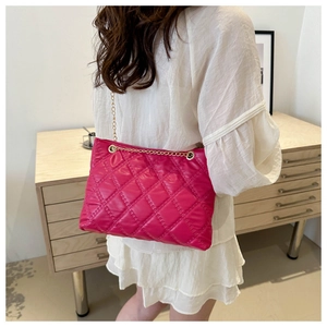 Detail of pink quilted shoulder bag with gold chain strap worn by a woman in white dress