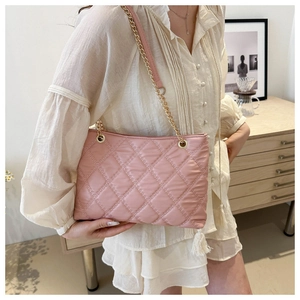 Detail of pink quilted shoulder bag with soft cloud texture and gold chain strap