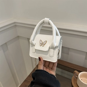 Elegant white mini ballerina handbag with bow detail and gold chain strap held by hand