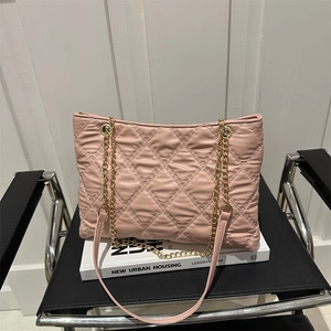 Pink quilted tote bag with golden chain straps shown on a white book backdrop