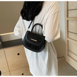 Rear view of a black pleated leather saddle bag with gold metal hardware on a model