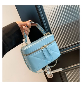 Detail of light blue quilted leather handbag with gold chain strap and top handle