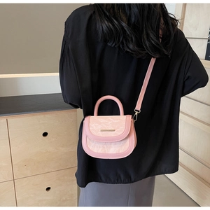Pink saddle bag with marble textured flap and gold buckle on a model shoulder