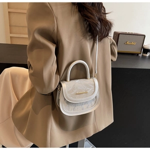 Detail of silver saddle bag with ice crack texture and metallic gold trim on a casual model