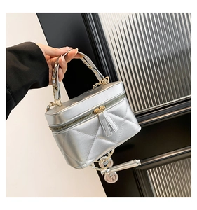 Detail of silver quilted bucket bag with metallic chain strap and sleek zipper closure