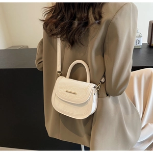 Detail of off-white crossbody saddle bag with wrinkled leather texture and gold metal bar