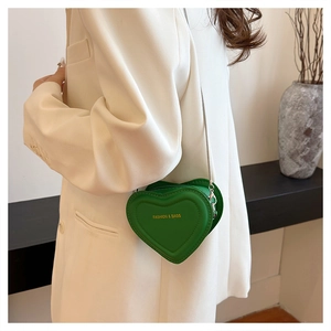 Close-up of green heart-shaped crossbody bag with gold FASHION & BAGS logo and chain