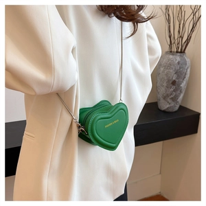 Detailed close-up of a vibrant green heart-shaped crossbody bag with gold fashion lettering