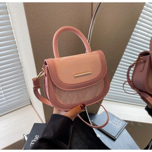 Detail of pink saddle bag featuring gold metal hardware and textured faux leather