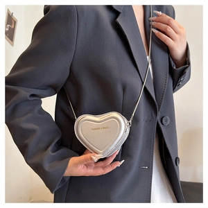 Close-up of mini heart-shaped silver chain bag worn over a grey blazer for daily fashion