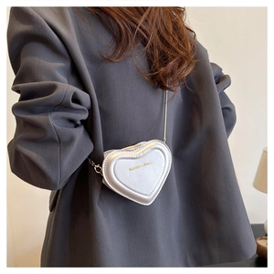 Detail view of heart-shaped silver crossbody bag with chain strap on a blazer