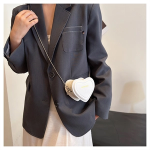 Close-up of white heart-shaped crossbody bag with gold fashion text and metal chain