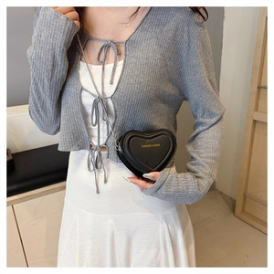 Close-up of heart-shaped black leather mini bag with gold chain and fashion lettering