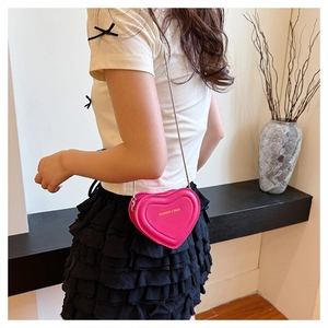 Close-up of bright pink heart-shaped mini bag with silver chain and embossed texture