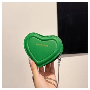 Macro shot of green heart-shaped quilted bag with gold logo and silver chain strap