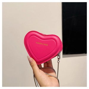 Detail of a pink heart-shaped mini bag with leather texture and silver chain strap