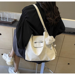 Detail of cream tote bag featuring a bow design and a cloud plush pendant charm