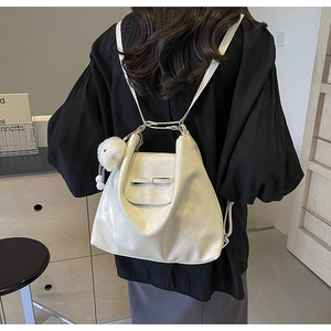 Detail of a creamy white bow backpack with a plush pom-pom and soft faux leather texture