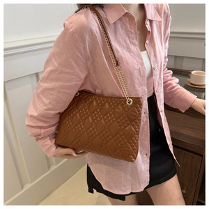 Caramel brown quilted shoulder bag with gold chain strap shown on a female model