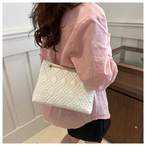 Detail shot of white quilted shoulder bag featuring gold chain and luxury diamond pattern