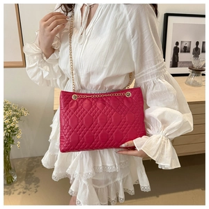 Detailed close-up of quilted red tote with elegant gold chain strap for luxury style