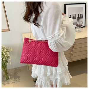 Detailed close-up of vibrant rose red quilted shoulder bag with gold chain strap