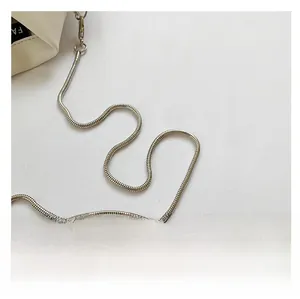 Detail of white leather handbag featuring a sleek silver metal snake chain strap