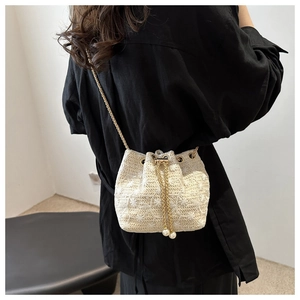 Detail of cream woven bucket bag with floral embroidery and pearl drawstring tassels