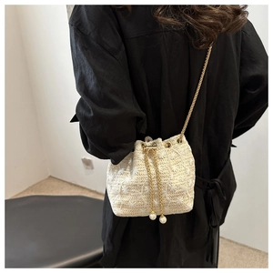 Detail of woven cream bucket bag with floral crochet pattern and pearl drawstring trim