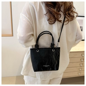 Détail du sac seau en cuir plissé noir avec lettrage mode et poignée à nœuds
