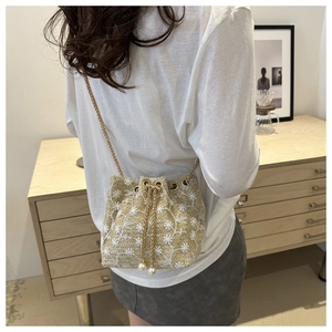 Detail of a beige woven bucket bag with white flower embroidery and pearl drawstring