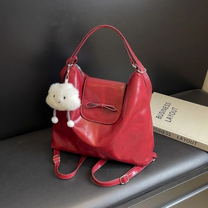 Dark red PU leather backpack with bow and cloud charm on a black leather bench