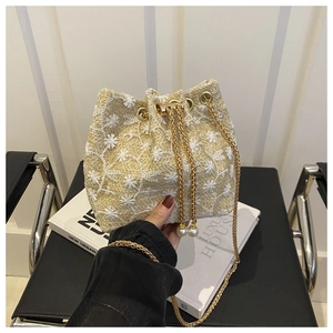 Detail of straw bucket bag with floral embroidery and pearl drawstring accents