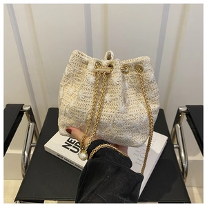 Close-up of straw bucket bag with floral embroidery, chain strap and pearl drawstring