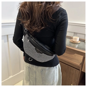 Gros plan d'un sac bandoulière noir avec des strass argentés et une plaque de logo