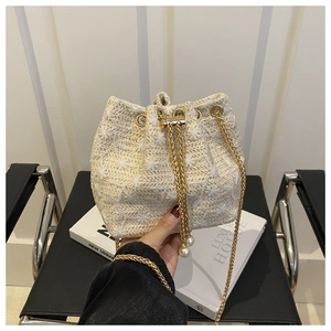 Detail of straw bucket bag with floral embroidery, gold chain strap and pearl charms