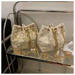 Detail of straw bucket bag with floral embroidery and gold pearl chain strap