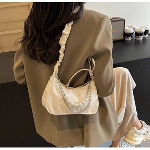 Detailed side view of cream ruched underarm bag featuring pearl and silver chain accents
