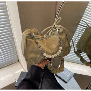 Detail of light green ruched baguette bag with pearl and silver chain shoulder strap