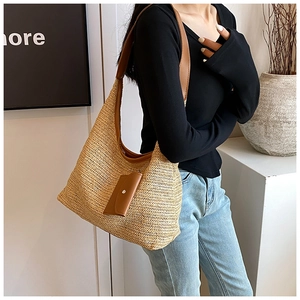 Detail of woven straw tote bag with brown leather shoulder strap and matching pouch