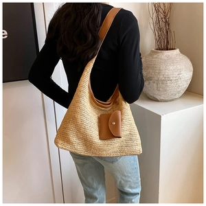 Detail of straw tote bag featuring brown leather straps and a small matching pouch