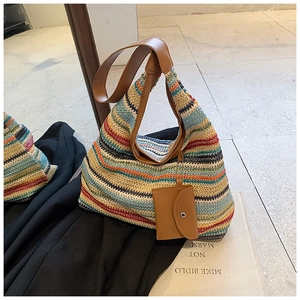 Detail of colorful striped straw tote bag with brown leather handles and small coin pouch