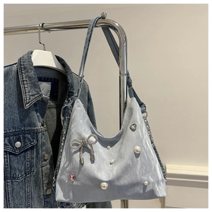 Detail of light blue pleated tote bag featuring white pearls and a bow pendant decoration