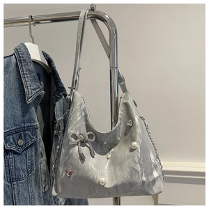 Close-up of metallic silver tote bag with pearl bow and pink heart gemstone detail