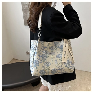 Detail of floral tote bag featuring chain shoulder strap and fashion label on canvas