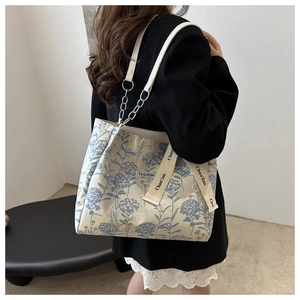 Detail of floral tote bag with white leather chain strap and woven lettered ribbon