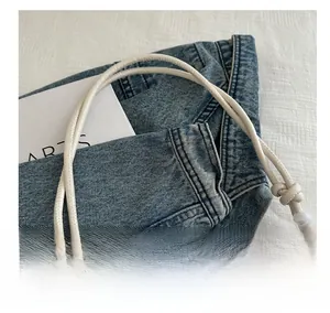 Detail of slim rounded leather handle with knot on cream embroidered cloud bag