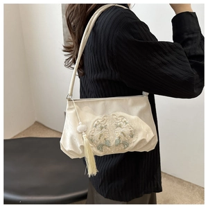 Detail of white embroidered shoulder bag with elegant tassel and floral pattern